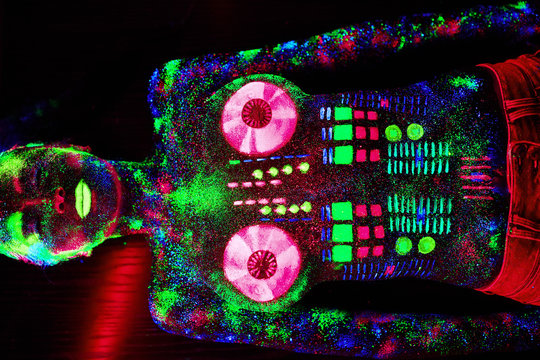 Concept. On the body of a girl painted DJ deck. Half-naked girl painted in UV colors.