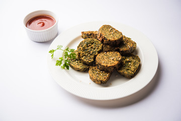 Cilantro cake or Kothimbir Vadi is a popular maharashtrian cuisine made with cilantro leaves. served with tomato ketchup. selective focus