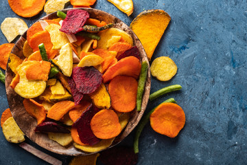 Dried vegetables chips from carrot, beet, parsnip and other vegetables on blue backgrounds. Organic diet and vegan food - 234945859