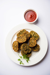 Cilantro cake or Kothimbir Vadi is a popular maharashtrian cuisine made with cilantro leaves. served with tomato ketchup. selective focus