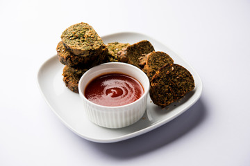 Cilantro cake or Kothimbir Vadi is a popular maharashtrian cuisine made with cilantro leaves. served with tomato ketchup. selective focus