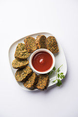 Cilantro cake or Kothimbir Vadi is a popular maharashtrian cuisine made with cilantro leaves. served with tomato ketchup. selective focus