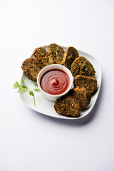 Cilantro cake or Kothimbir Vadi is a popular maharashtrian cuisine made with cilantro leaves. served with tomato ketchup. selective focus