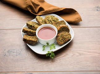 Cilantro cake or Kothimbir Vadi is a popular maharashtrian cuisine made with cilantro leaves. served with tomato ketchup. selective focus