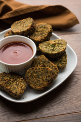 Cilantro cake or Kothimbir Vadi is a popular maharashtrian cuisine made with cilantro leaves. served with tomato ketchup. selective focus