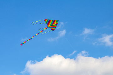 Colorful kite flying in the blue sky with wind.