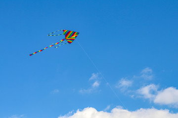 Colorful kite flying in the blue sky with wind.