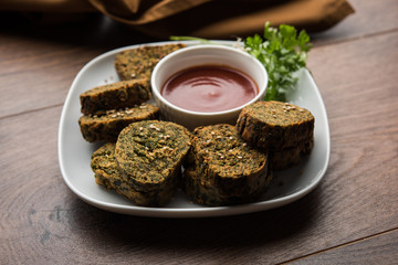 Cilantro cake or Kothimbir Vadi is a popular maharashtrian cuisine made with cilantro leaves. served with tomato ketchup. selective focus