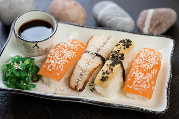 Plate of nigiri sushi with salmon, eel, tamago omelette, seaweed salad and soy sauce, close-up
