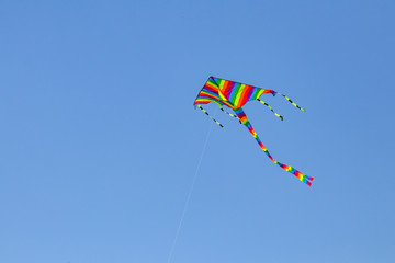 Colorful kite flying in the blue sky with wind.
