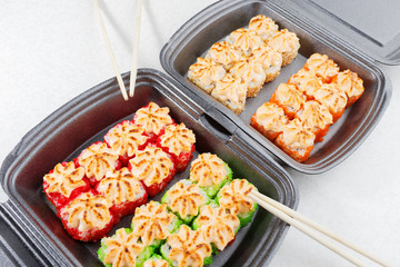 Sushi in plastic packaging. Baked sushi and chopsticks.