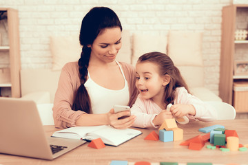 Happy Little Girl and Mother with Phone at Home.