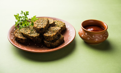 Cilantro cake or Kothimbir Vadi is a popular maharashtrian cuisine made with cilantro leaves. served with tomato ketchup. selective focus