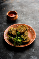 Cilantro cake or Kothimbir Vadi is a popular maharashtrian cuisine made with cilantro leaves. served with tomato ketchup. selective focus