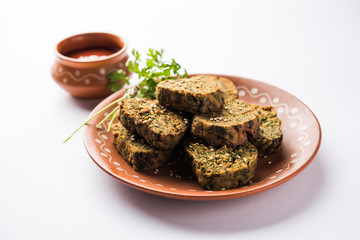 Cilantro cake or Kothimbir Vadi is a popular maharashtrian cuisine made with cilantro leaves. served with tomato ketchup. selective focus