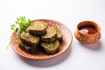 Cilantro cake or Kothimbir Vadi is a popular maharashtrian cuisine made with cilantro leaves. served with tomato ketchup. selective focus