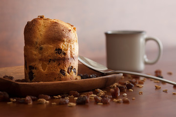 PLUM CAKE SOBRE CUENCO DE MADERA RODEADO DE PASAS Y CON TAZA BLANCA DE CAFÉ