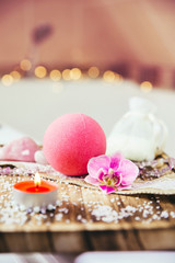Pink bath ball with orchid flower, scented candle and bath salt on wooden tray in bath room. Therapy concept. Taking a relaxing bath.
