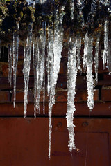 Icicles hanging on roof dripping close up. Beautiful element of winter or spring design
