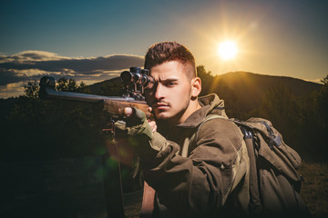 Close up snipers carbine at the outdoor hunting. Hunter aiming rifle in forest. Hunter with shotgun...