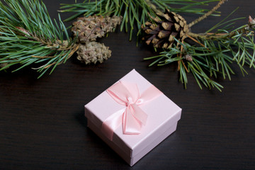 Fototapeta na wymiar Wrapping presents. Gift boxes. Nearby is a branch of pine with cones. Against a dark background.