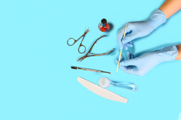 Manicure tool in the hands of the master. set of manicure accessories on blue background top view. flat lay composition with copy space. the concept of personal protective equipment