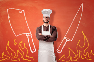 A bright orange background with drawn flames, a cleaver, a knife and a serious male cook standing...