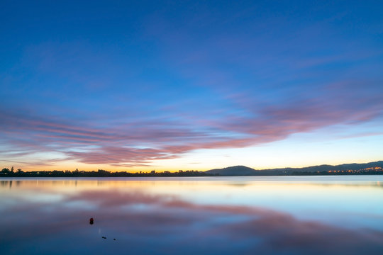 Calming effect of long exposure sunrise over bay in pink and blue hues.