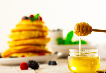 Honey with wooden honey dipper on wooden table