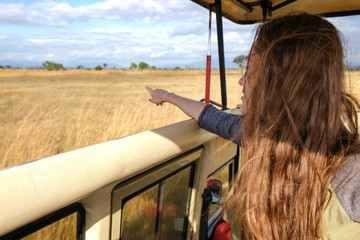 Young woman discover african nature by car Tanzania safari Point with finger