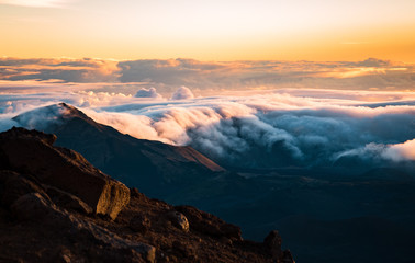 Beautiful Colorful Sunrise Sky at Dawn with Layer of Clouds Covering Mountain Tops from the Top of Haleakala Volcano in Maui Hawaii in Background of Amazing Landscape in Island Paradise