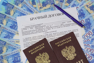 Against the background of Russian paper money is a form of marriage contract, a pen and two passports
