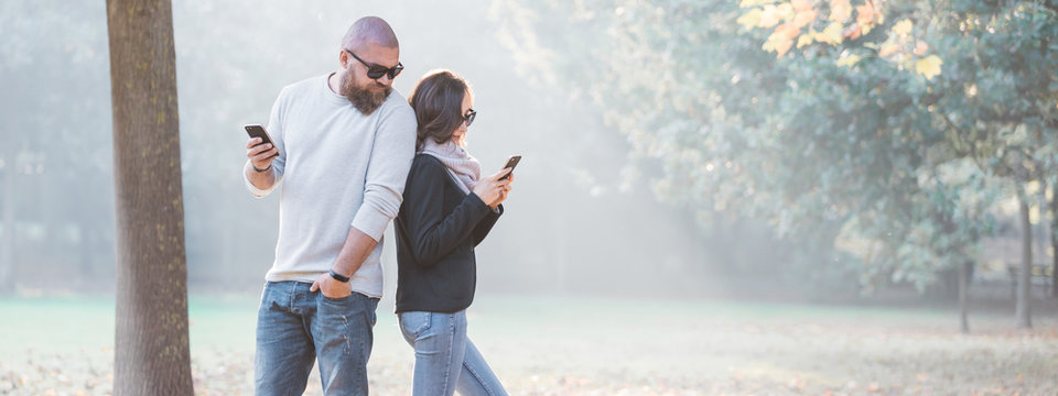 Banner Image Of A Man Spying On What His Girlfriend Is Writing On Her Smartphone. Trust And Jealousy In A Couple Concept.