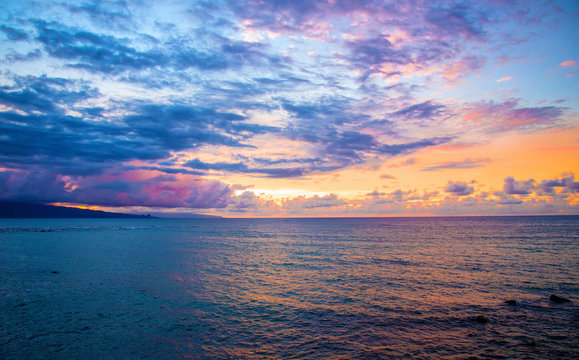 Beautiful Crystal Clear Blue Water with Reflection of Colorful Sunset Sky and Mountain Silhouette in in Scenic Background of Tranquil Tropical Island Paradise Nature Scene of Maui Hawaii
