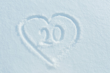 A figure of twenty  written in the snow in the painted heart. Snow texture.