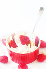 Healthy raw vegan dessert - banana and strawberry with coconut cream and coconut chips on white background