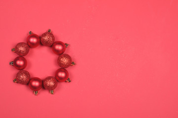 Red Baubles forming a Christmas wreath on red background.