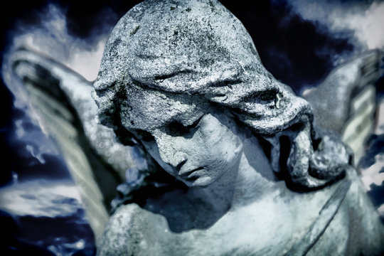 Beautiful sad angel marble sculpture looks down. Pain, religion, faith concept.