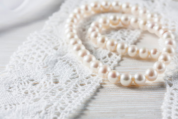 Fototapeta na wymiar White pearl necklace on handmade lace background.