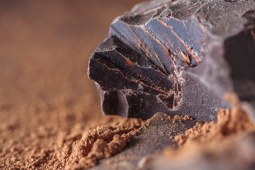 dark chocolate, cocoa solids and cocoa powder over wooden background