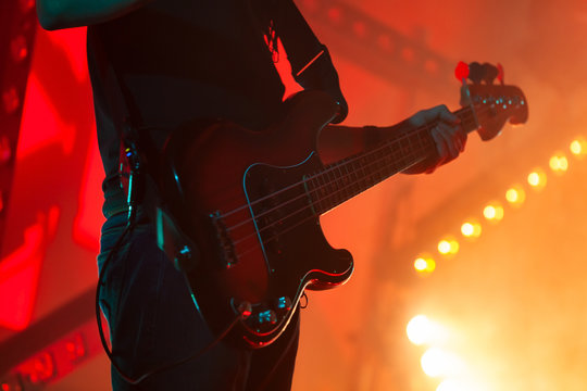 Electric bass guitar player in bright stage lights