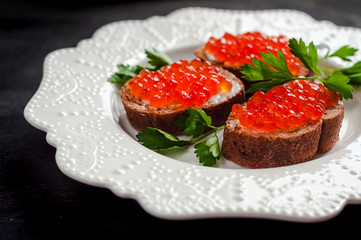 red caviar on black bread with butter. Healthy food. Fish appetizer. dark background