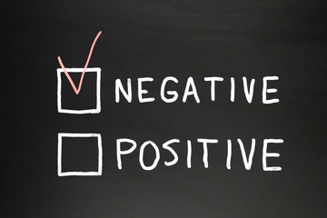 Negative and positive written on a black slate with chalk. In red marked negative box, conceptual...
