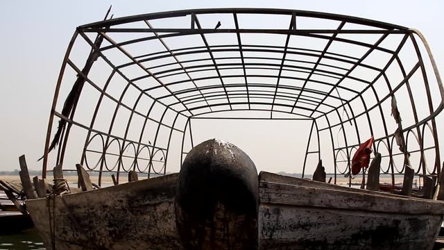 The boat stands in under a metal frame (boathouse) on the water of the Arabian sea. On the frame sit down Drongo
