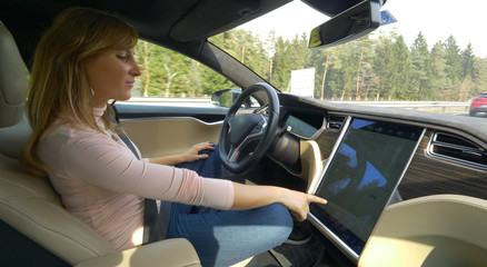 CLOSE UP Smiling woman setting up the navigation in her high tech autonomous car