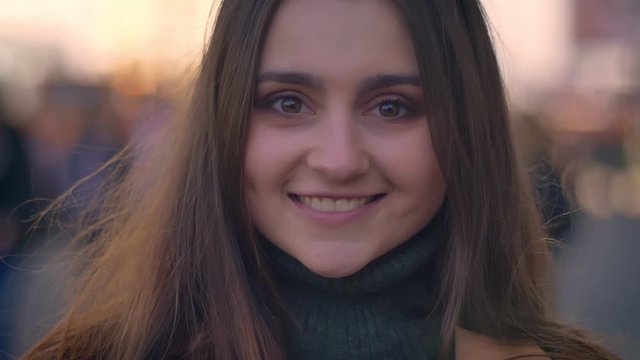 Close-up artistic caucasian girl with beautiful long brown is looking at camera chill and calmly standing in urban area