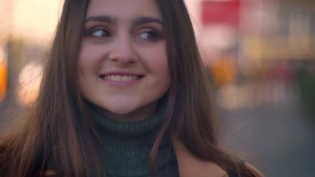 Footage of confident jolly caucasian female who is standing relaxed and looking straight at camera close-up, natural sight and calm vibes