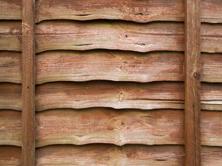 Close-up of a faded and weathered brown larch lap wooden fence panel. Rustic textured background or...