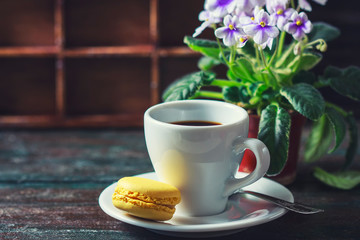 Beautiful breakfast. Morning cup of coffee with colorful macarons, on with flowers on dark background with copy space.