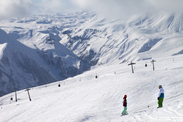 Fototapeta na wymiar Two snowboarders descend on snowy ski slope